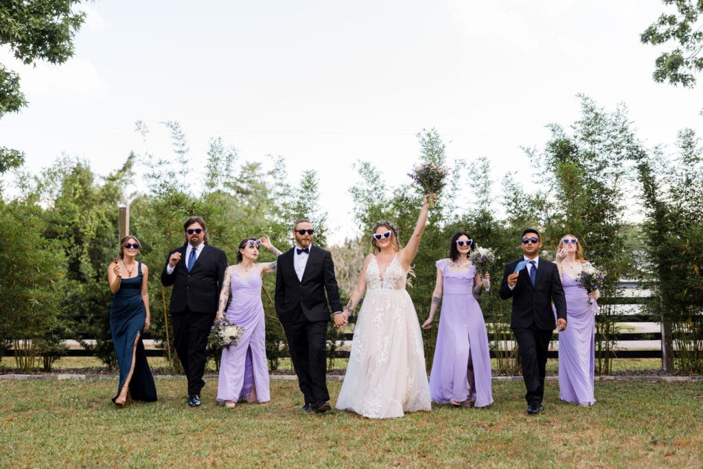 Modern, stylish wedding party walking confidently in a field—celebrating personality, fun, and a wedding that reflects your unique vibe.